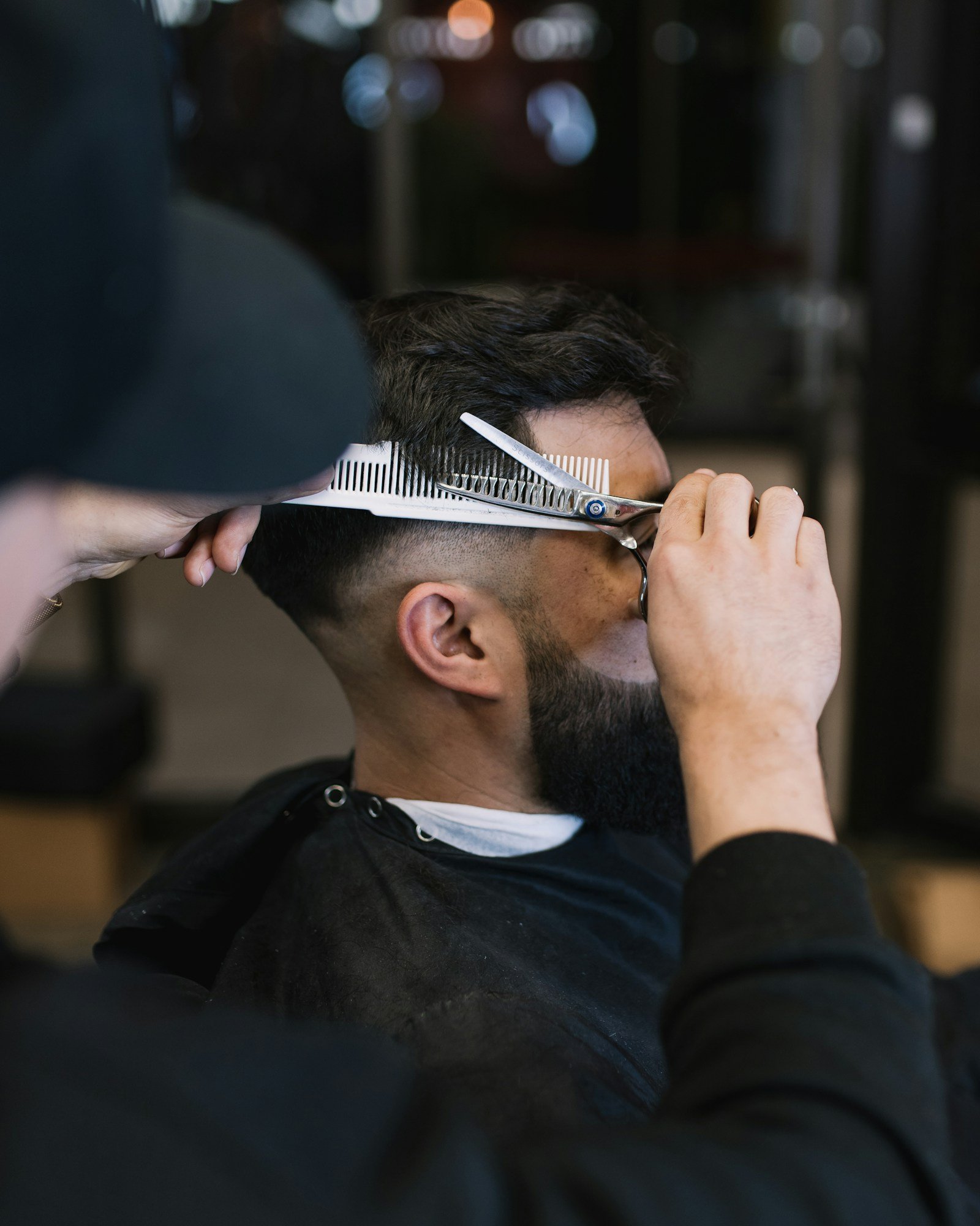 Barber cutting a client's hair with scissors