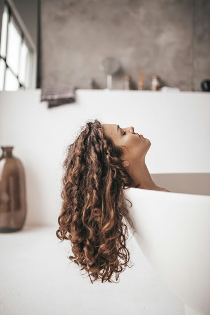 Curly hair being combed through during a morning bathroom routine